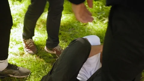 Teens kick a guy. Teens fighting, conflict, street violence. Medium shot. Stock Footage 118701703