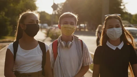 Teens with protective masks walk down the street Stock Footage 137906927
