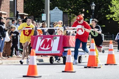 Teens push bed down city street in charity fundraising event Stock Photos