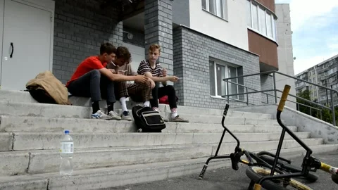 Teens resting and smoke on steps at the entrance Stock Footage 134433673