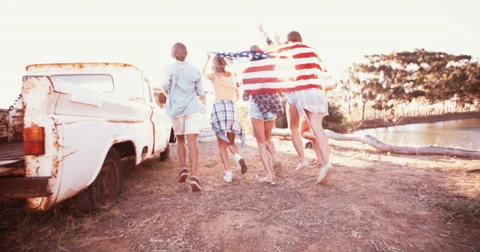 Teens running with an American flag in sun flare Stock Footage