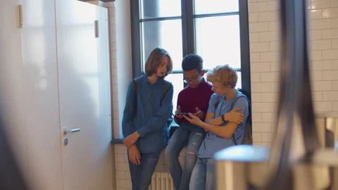Teens schoolboys having fun watching social media content on mobile phone in Stock Footage 233909677