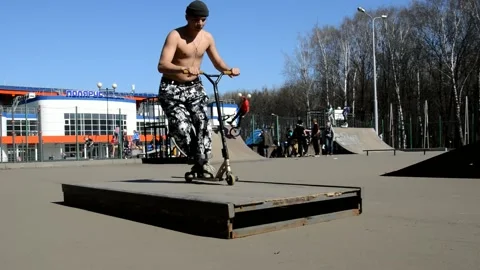 Teens on scooters performs a tricks in the skatepark Stock Footage 131351528