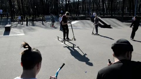 Teens on scooters performs a tricks in the skatepark Stock Footage 131404454