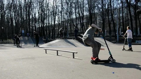 Teens on scooters performs a tricks in the skatepark Stock Footage 131404670