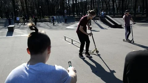 Teens on scooters performs a tricks in the skatepark Stock Footage 131404797