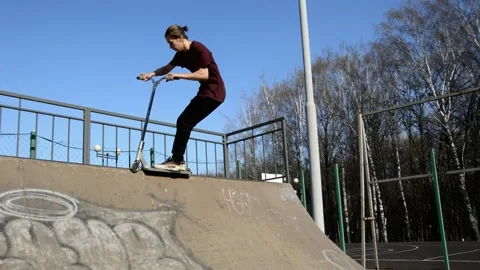 Teens on scooters performs a tricks in the skatepark Stock Footage 131406280