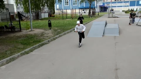 Teens on scooters performs a tricks in the skatepark Stock Footage 132845393