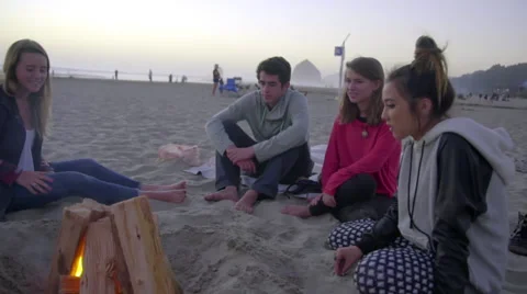 Teens sit by a fire together Stock Footage 53232827