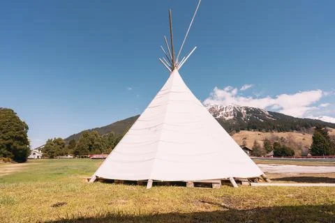 A teepee is standing in a field with a mountain in the background Stock Photos