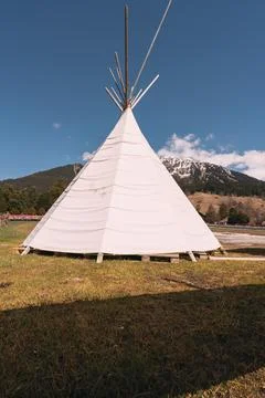 A teepee is standing in a field with a mountain in the background Stock Photos