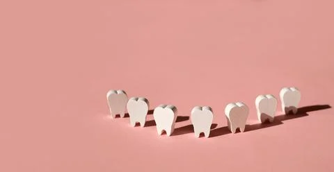 Teeth models standing in a row making a smile on a pink background. Foto stock