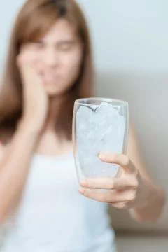 Teeth Sensitive to Cold concept. woman hold Ice Water glass and having toot.. 库存照片