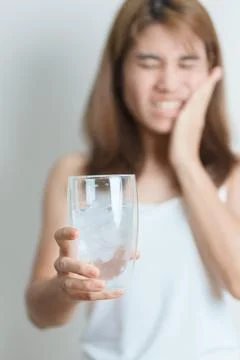 Teeth Sensitive to Cold concept. woman hold Ice Water glass and having toot.. 写真素材