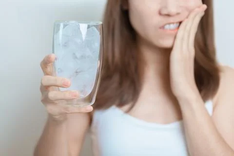 Teeth Sensitive to Cold concept. woman hold Ice Water glass and having toot.. 库存照片