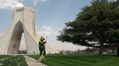 Tehran, using a broom to sweep grass from pathway, Azadi Tower Video stock 33922995