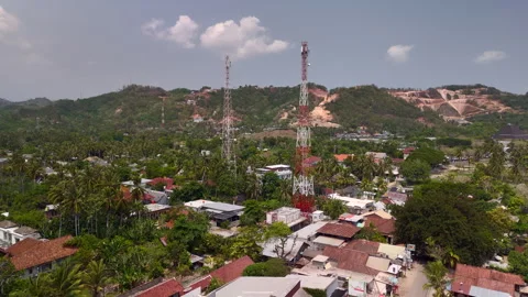 Telecom towers above small town with palm trees and hills in background Stock Footage 328623625