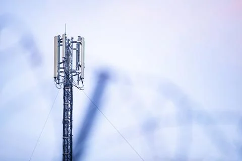 Telecommunication 5G cellular network tower against pastel sky background Stock Photos