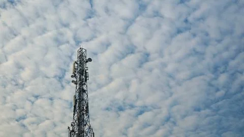 Telecommunication tower against a bright cloudy blue sky Stock Photos