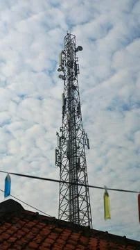 Telecommunication tower against a bright cloudy blue sky Stock Photos