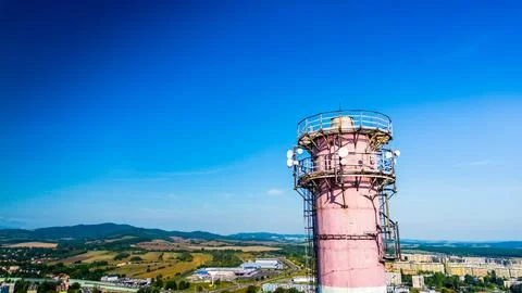 Telecommunication tower with antennas overlooking green hills and blue sky Stock Photos