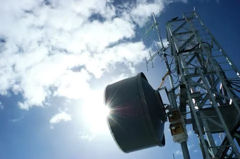 Telecommunication tower in back-light against a cloudy blue sky Stock Photos