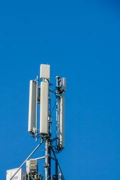 Telecommunication tower with multiple antennas and cables under bright blue s Stock Photos