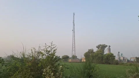 Telecommunications Cell Tower In Green Rural Field Against Clear Sky Stock Footage 344557703