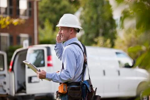 Telecommunications installer using work order at his truck and talking on a c Stock Photos