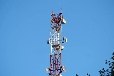Telecommunications tower with a 5G cellular network antenna on a blue sky bac Stock Photos