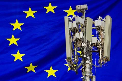 Telecommunications tower with a 5G cellular network antenna agains flag of EU Stock Photos