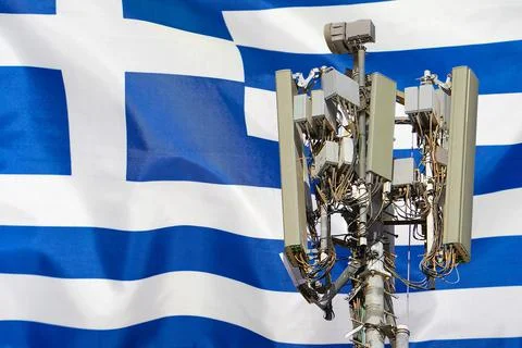 Telecommunications tower with a 5G cellular network antenna agains flag of Gr Stock Photos