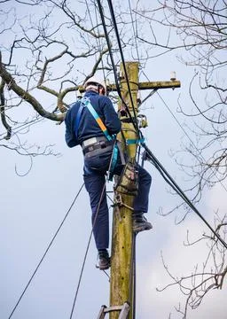 Telecoms engineer climbing telegraph pole, phone line repair UK Stock Photos