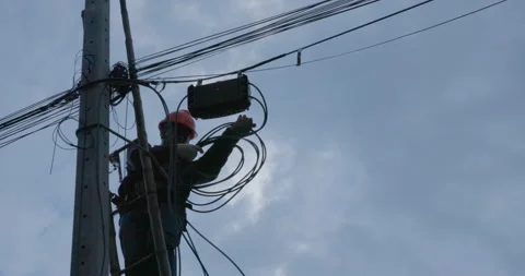 A telecoms worker is shown working from a utility pole ladder while wearing high Stock Footage 212622841