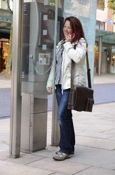  Telefonieren Eine junge Frau telefoniert mit einem öffentlichen Telefon. .. Stock Photos