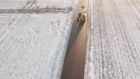Telehandler Driving Along Rural Winter Road Between Snow Covered Fields at Stockbeeldmateriaal 331075139