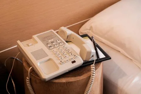 A telephone and notebook with bed, orange lighting close up at the hotel bedr Stock Photos