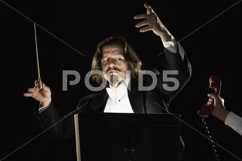 Telephone being handed to orchestral conductor Stock Photos