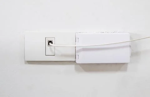 The telephone cable connects to the socket on the house wall for the internet Foto stock