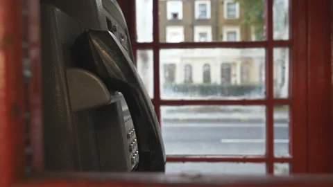 A telephone inside a red booth beside a road. Stock Footage 134914863