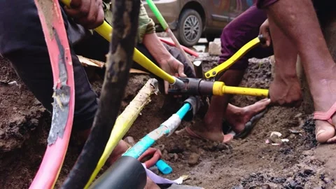 Telephone lineman align protected wiring inside open trench Stock Footage 314177518