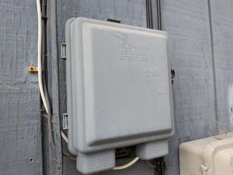 A telephone network interface mounted on the side of a building Stock Photos
