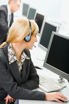 Telephone operator is looking at the monitor with her hand on the mouse Stock Photos