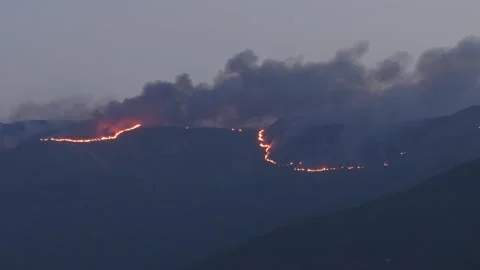 Telephoto drone view of continuous wildfire firelines and dense smoke on Stock Footage 345551287