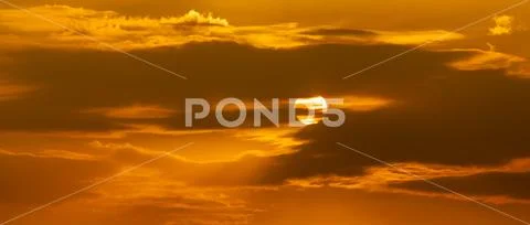 Telephoto photo of yellow orange sunset sunrise, clouds, sky golden hour Stock Photos