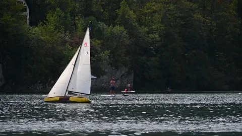 Telephoto view of small train sailing yacht boat float in Bohinj lake Stock Footage 170649205