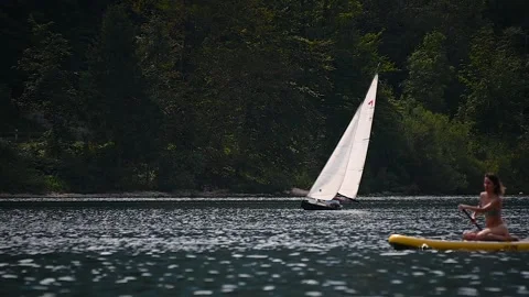 Telephoto view of small train sailing yacht boat float in Bohinj lake Stock Footage 170649227