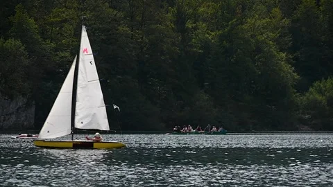 Telephoto view of small train sailing yacht boat float in Bohinj lake Stock Footage 170650860