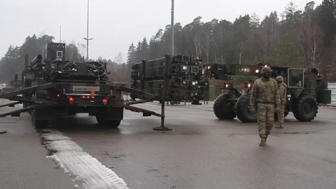 Telescopic handler unloading Patriot missile from truck with outriggers extended Stock Footage 102707713