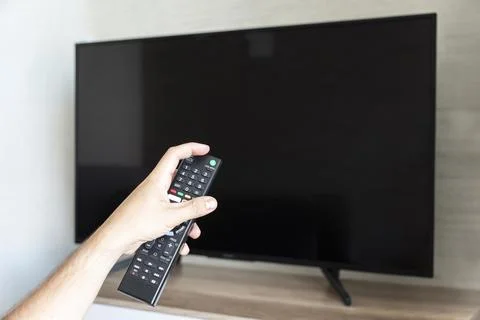 Television remote control changes channels thumb on the TV screen Stock Photos
